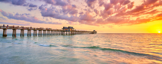 Image of a pier extending into the ocean at sunset.