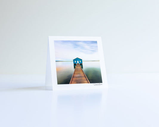 a postcard of a lake house with gradient sky