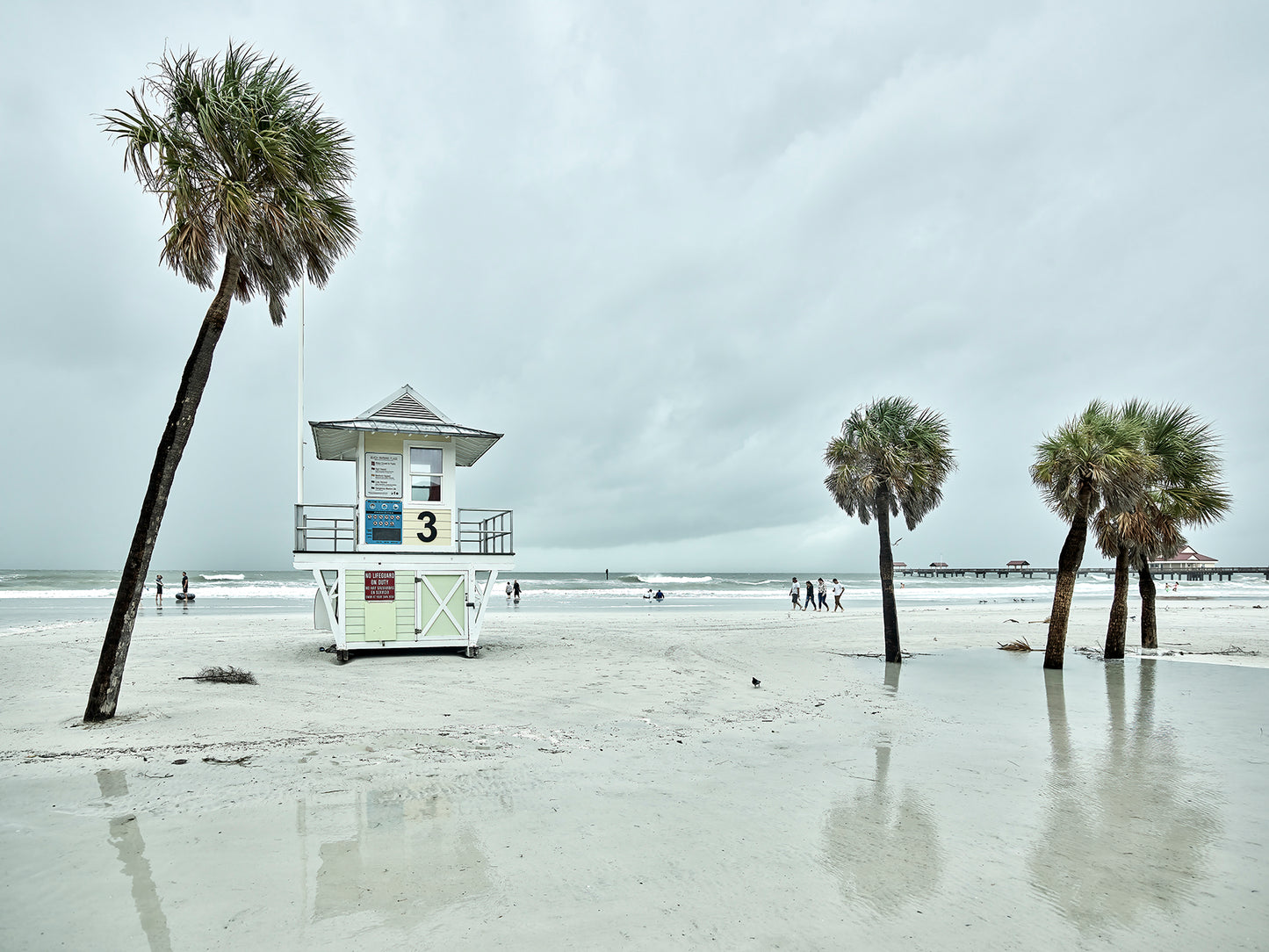 Image of beach with lifeguard stand and palm trees.
