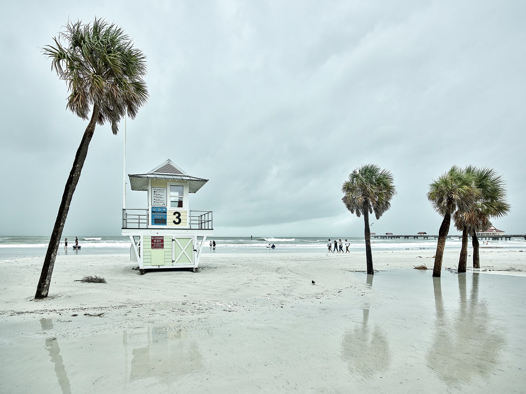 Image of beach with lifeguard stand and palm trees.