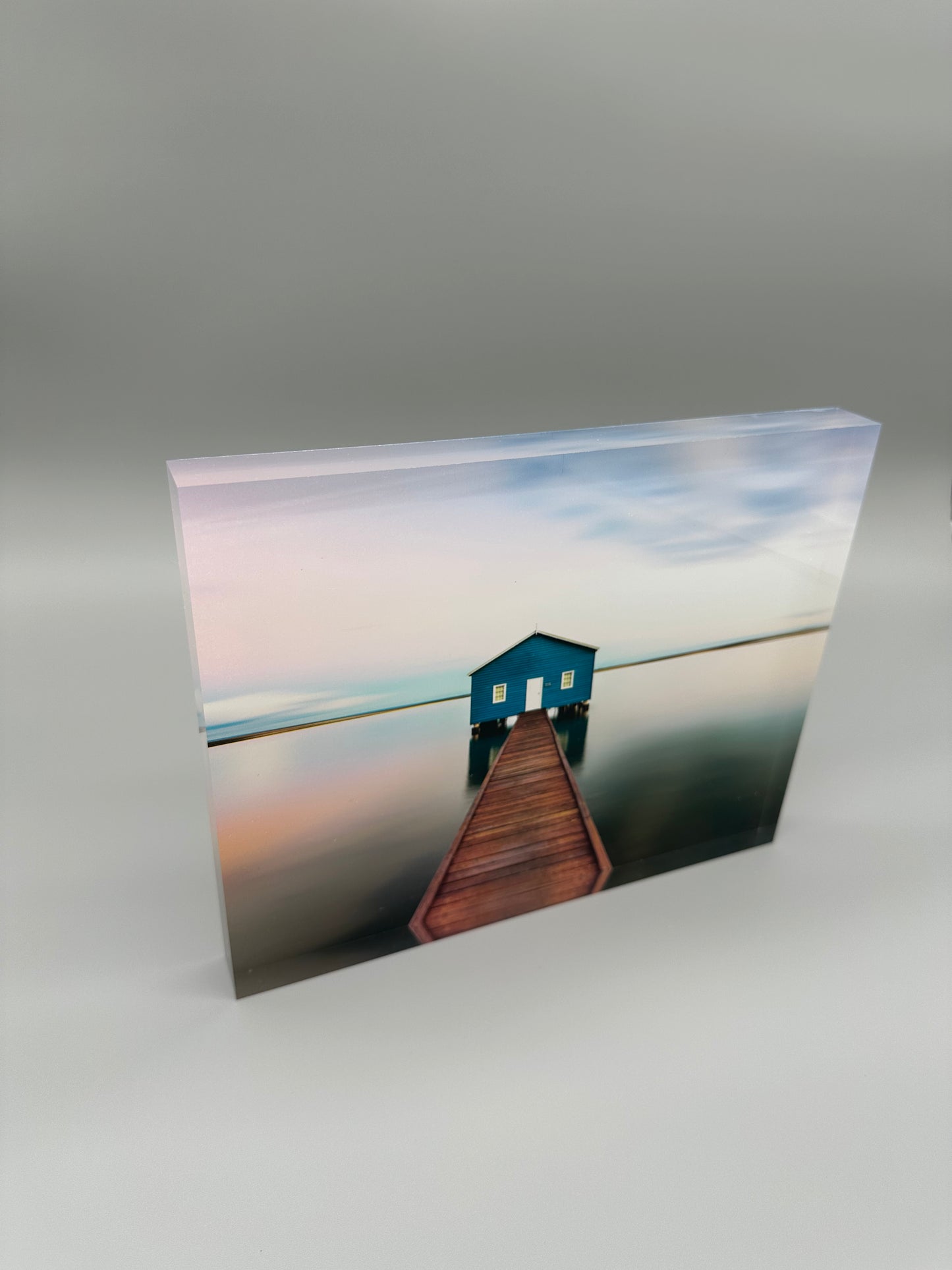 Acrylic print with a blue house and wooden pier on a gray background