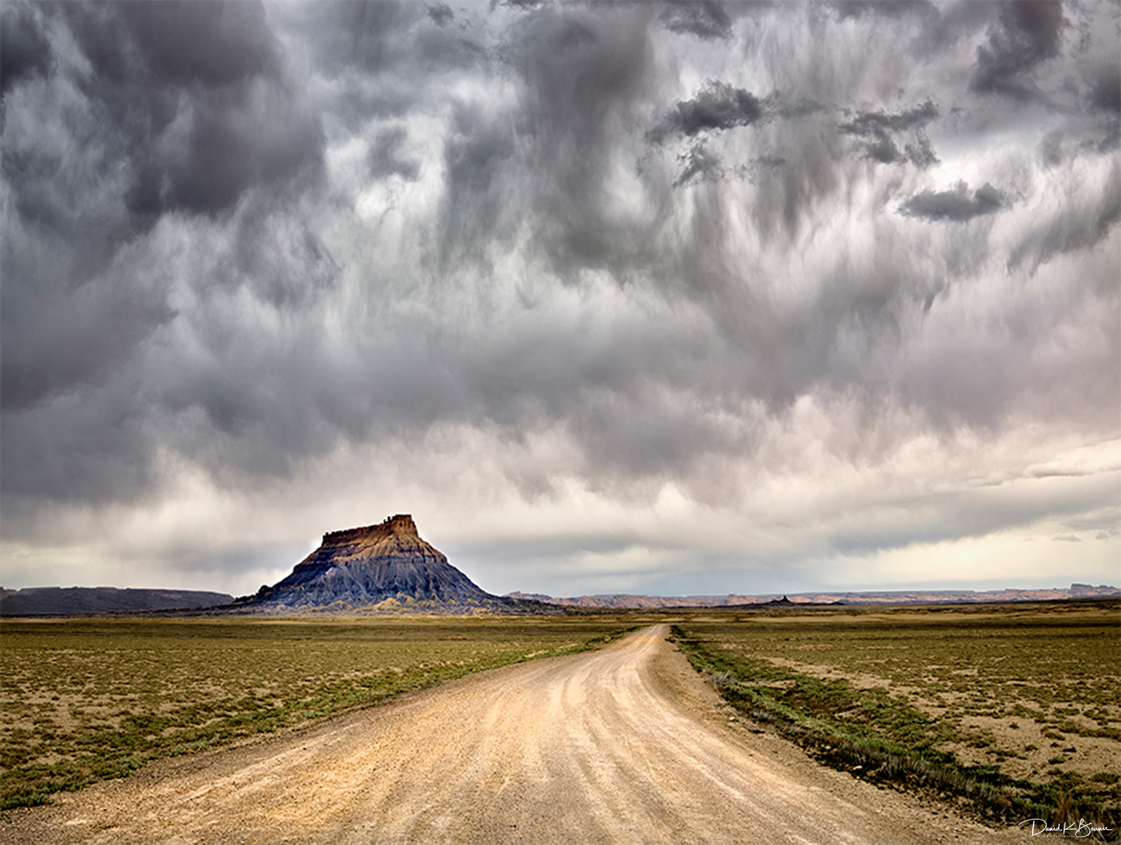 empty highway in desert with dark, grey, cloudy skies.