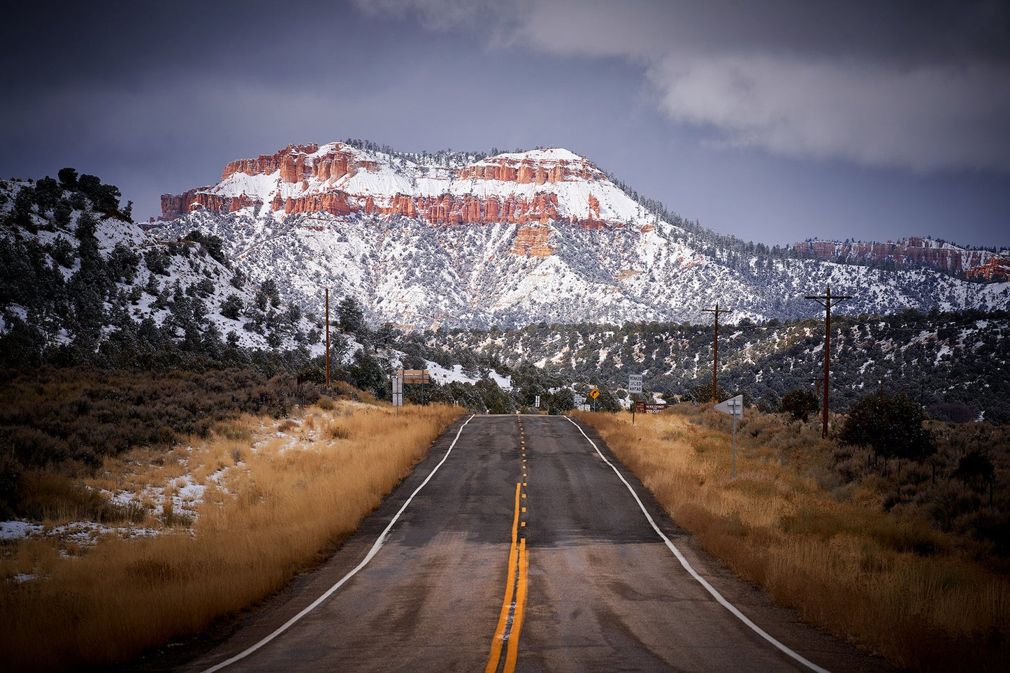 snow covered mountain, behind long, straight road