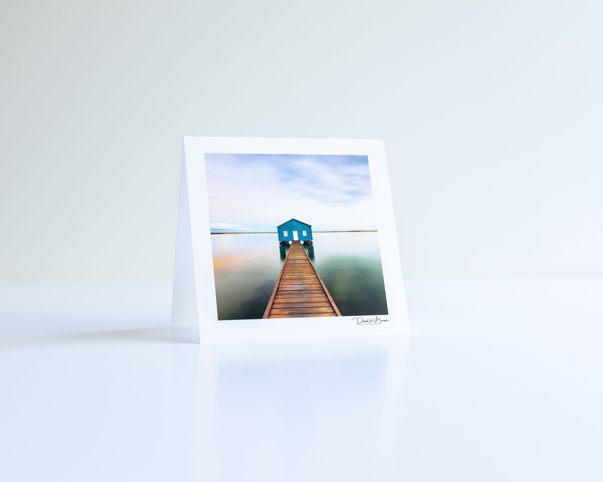 a postcard of a lake house with gradient sky